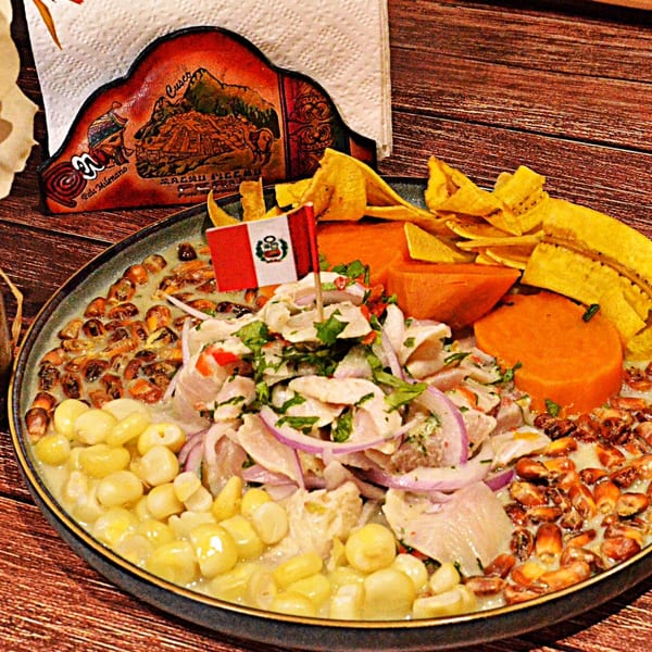 Peruvian ceviche with fish, red onion, corn, sweet potato, plantain chips, and a Peruvian flag.