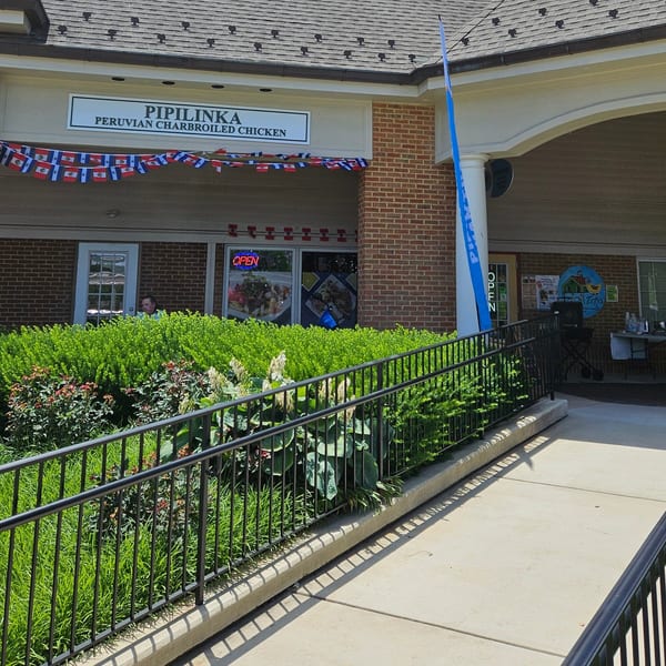 The exterior of Pipilinka Peruvian Charbroiled Chicken restaurant with a ramp and Peruvian flag bunting.