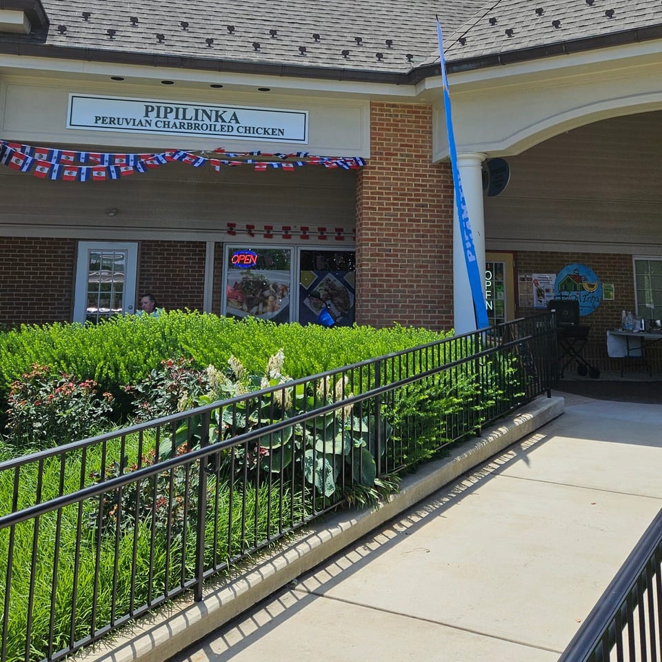 The exterior of Pipilinka Peruvian Charbroiled Chicken restaurant with a ramp and Peruvian flag bunting.